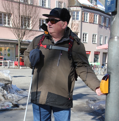 Ein Herr mit Sonnbrille drückt auf den Knopf einer Signalampel