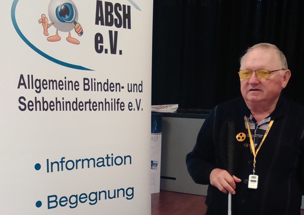 Kurt Reinert stehend vor einem Banner des ABSH e.V.